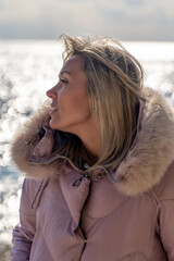 Woman Coastline Winter Jacket: Outdoor portrait, blonde woman seaside, cold weather, contemplative mood. © svetograph