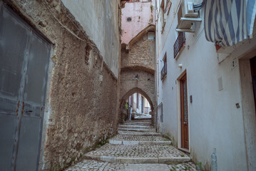 Obraz premium Gaeta, Latina, Italy: Cobblestone street with archway and buildings in Italian town