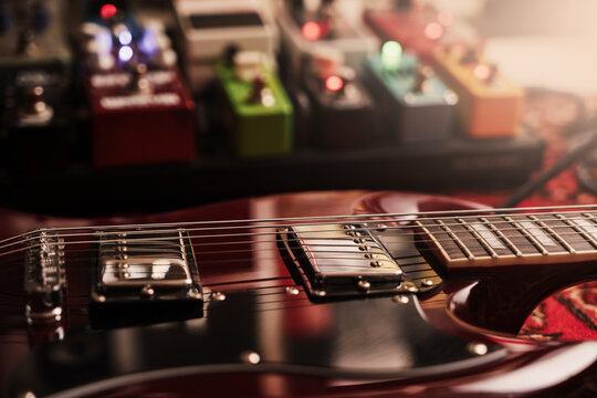 electric red sg guitar and pedalboard on a carpet. pedal effects fx background. Selective focus