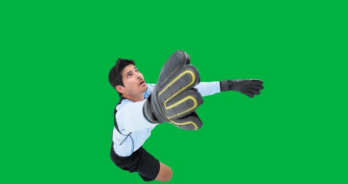 Caucasian male soccer goalkeeper making a save against black background