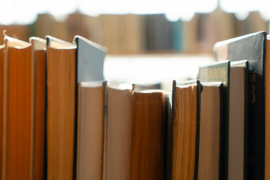 Old books on the bookshelf in library archive interior in sunny day. Shallow depth of field