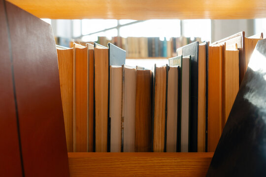 Old books on the bookshelf in library archive interior in sunny day. Shallow depth of field