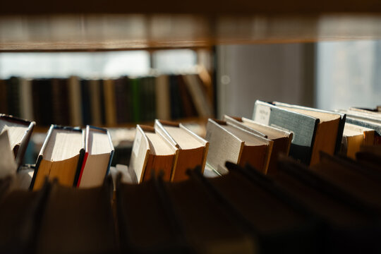 Old books on the bookshelf in library archive interior in sunny day. Shallow depth of field