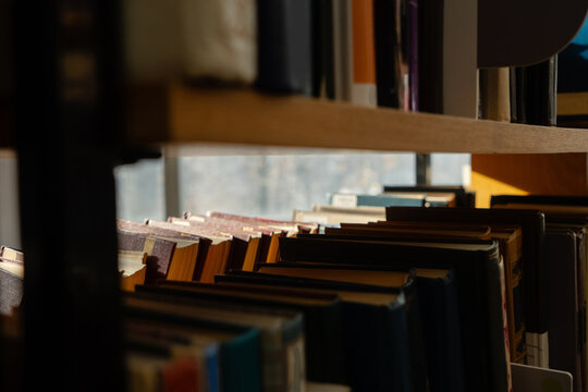 Old books on the bookshelf in library archive interior in sunny day. Shallow depth of field