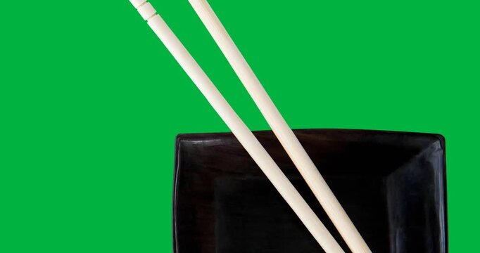 Overhead view of chopsticks over a black bowl on black surface