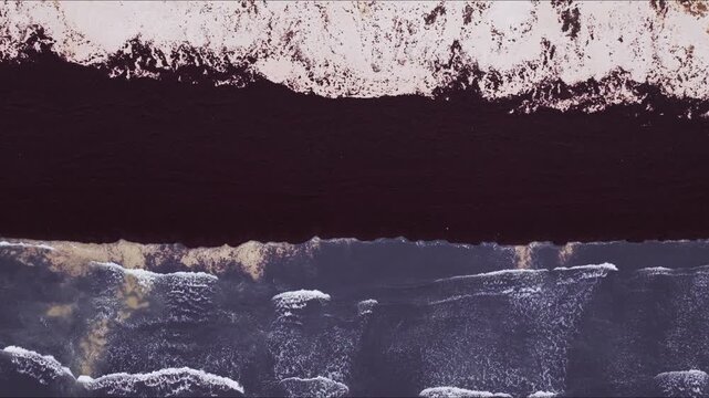 Top down cinematic shot of waves reaching shore with dark algae stripe