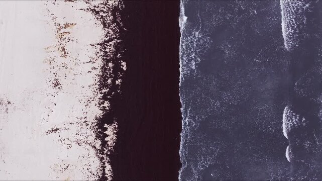 Aerial footage of waves reaching beach with seaweed lines along shoreline