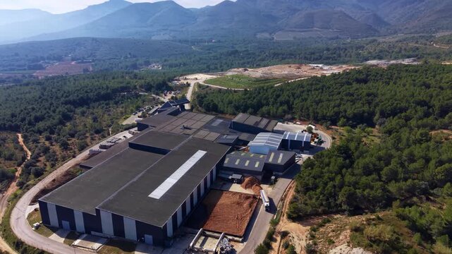 Urban waste processing plant surrounded by forested mountains, converting municipal solid waste into recovered solid fuel, biofuel, biogas, and bio compost