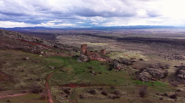 Castle of Zafra perched on a sandstone ridge in Spain, medieval fortress towers rising from dramatic rocky outcrop overlooking vast open plains under cloudy skies