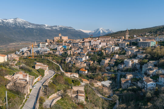 Aerial view of the historic town of Capestrano and Castello Piccolomini with snow-capped mountains in the background, Capestrano, Abruzzo, Italy.