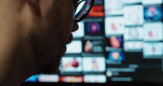 Close-up side view of a person wearing glasses watching multiple digital screens, representing media consumption, data monitoring, and modern digital environments.