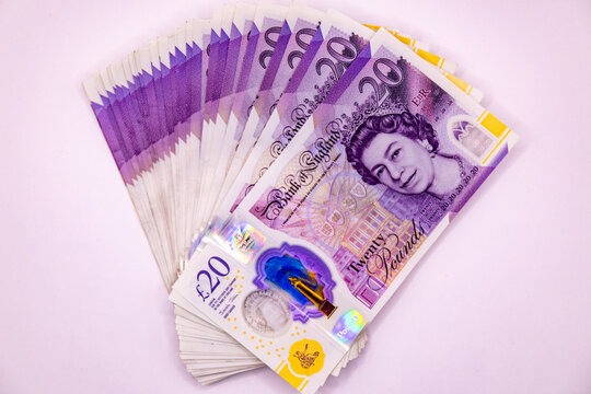 A stack of twenty pound banknotes from the Bank of England featuring Queen Elizabeth II, isolated on white background