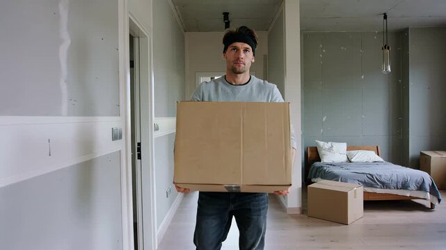 Man carrying large cardboard box walking in new apartment during move
