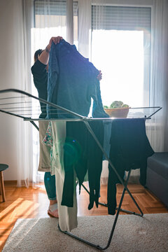 Woman drying laundry on a rack at home.