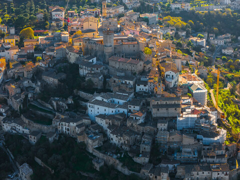 Aerial view of the medieval Castello Piccolomini and the historic stone rooftops of the hillside village in Capestrano, Abruzzo, Italy.