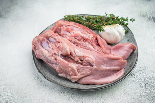 Raw lamb tongues on ceramic plate with thyme and garlic isolated on white background fresh organ meat ingredient for traditional cooking