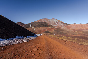 Dirt road to colorful mountain landscape with snow patches © lucegrafiar