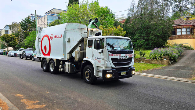 garbage truck australia.Veolia Australian waste company.Truck collects waste from residential street in the morning near houses and parked cars