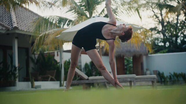 Woman practicing yoga asana trikonasana in garden