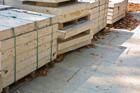 WOODEN PALLET WITH NEW TRAVERTINE STONE SLABS READY FOR INSTALLATION ON URBAN CONSTRUCTION SITE PAVEMENT