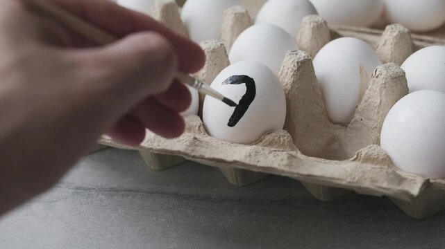 Close-up of painting a white egg with a paintbrush