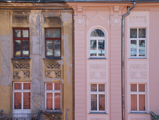 Fototapeta premium Side by side contrast of old weathered and newly renovated building facades in city. Architectural comparison showing decay, restoration, and urban renewal concept. Detailed exterior with windows.