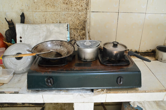 A centered high angle perspective looking down at various cooking pots, a frying pan, and kitchen accessories arranged on a gas cooktop ready for meal preparation.