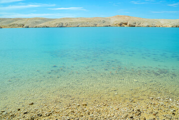 Obraz premium Pag Island, Croatia, Life on Mars Trail: Rocky beach and clear turquoise water with hills