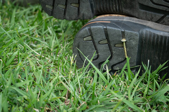 Screw stuck in the sole bottom of a men's work boot. Work safety equipment.