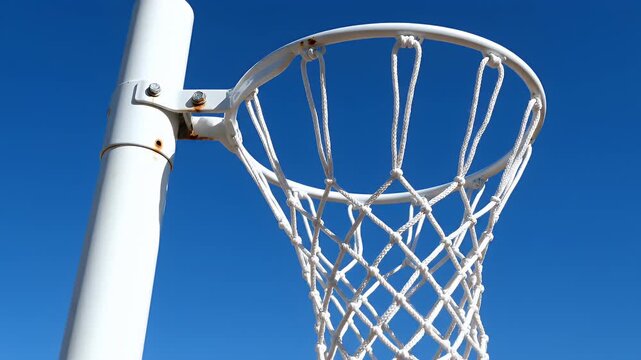 Close-up of a white netball net against a clear blue sky.