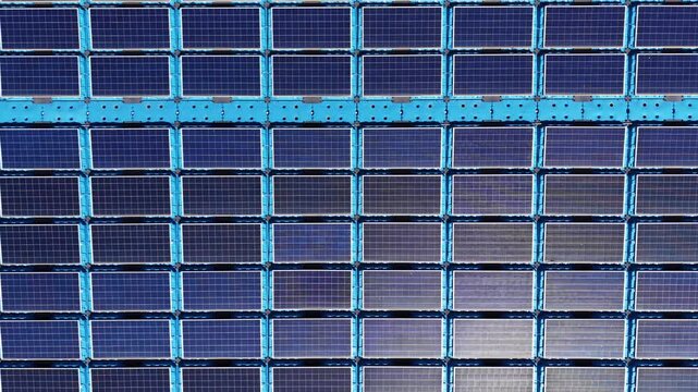 Close-up top-down view of floating solar farm panels with blue structural frames, photovoltaic cell arrays showing monocrystalline silicon modules and reflective surface details