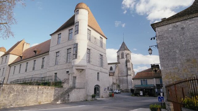 Ancient cut stone architecture with a circular turret under the sun in Issigeac. Slow motion tracking shot.