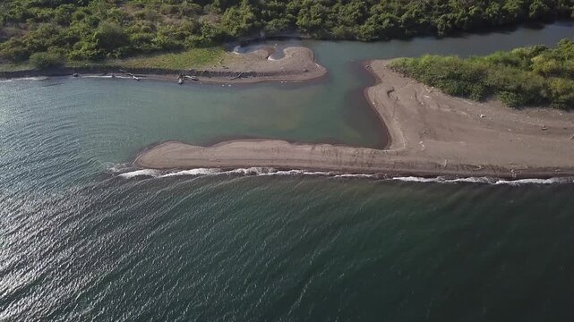 river delta along the narrow, white sandy beach of a rural town.  Drone, aerial