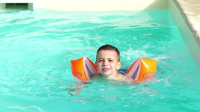 Happy Child Learning to Swim with Arm Floaties, slow motion 
