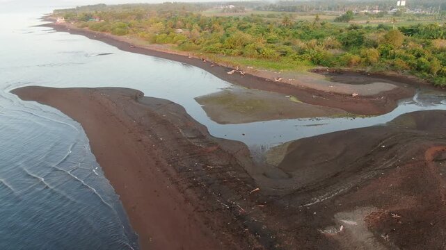 river delta along the narrow, white sandy beach of a rural town.  Drone, aerial