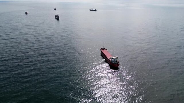 Aerial view of cargo ships anchored in the open sea at sunny day