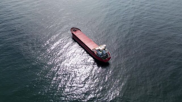 Aerial view of a red cargo ship sailing in the open blue ocean
