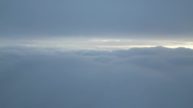 Aerial View Above Thick Clouds with Sun Peeking Through Horizon