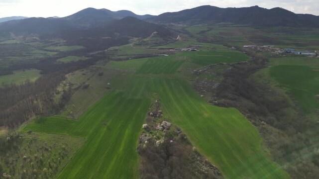 Aerial panoramic view of green hills and rural village in mountain valley