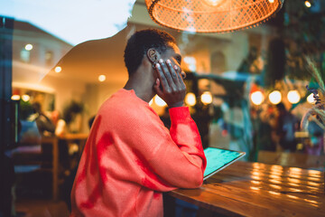 Pensive young woman looking away with inspiration while working on her digital tablet in a stylish...