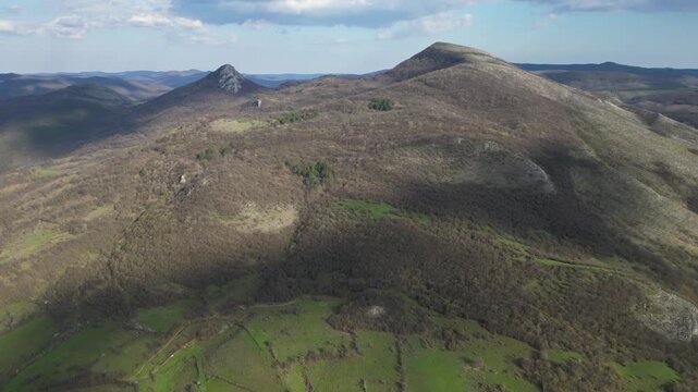 Aerial panoramic view of green hills and rural village in mountain valley