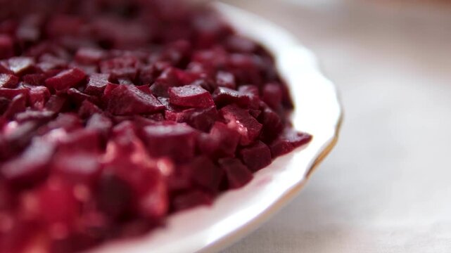 A modern version of Ukrainian shuba salad served on a white plate with beetroot cut into cubes instead of grated layers. deconstructed herring under fur coat salad with a fresh presentation style.