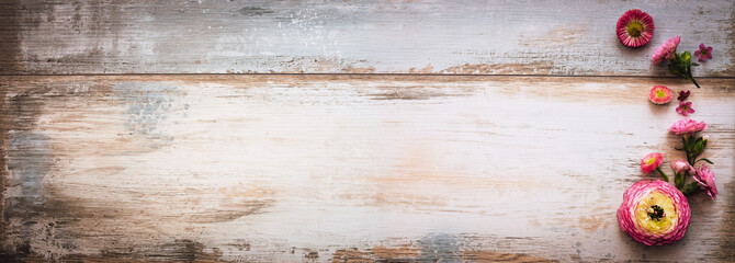 Naklejka premium Purple flowers on vintage wooden background. Top view of rustic wooden banner with space for text. Ideal for a mother's day greeting card.