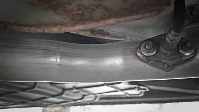 the undercarriage of a vehicle, an exhaust pipe with an oxygen sensor attached. automotive
