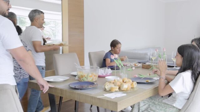 Hispanic man bringing food to dining table during family celebration