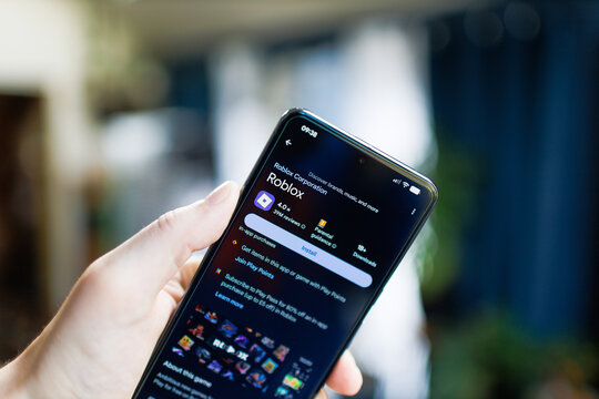 mobile phone in hand with Roblox app on the google play store