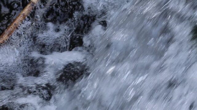 Rushing water flowing down a river over rocks in slow motion