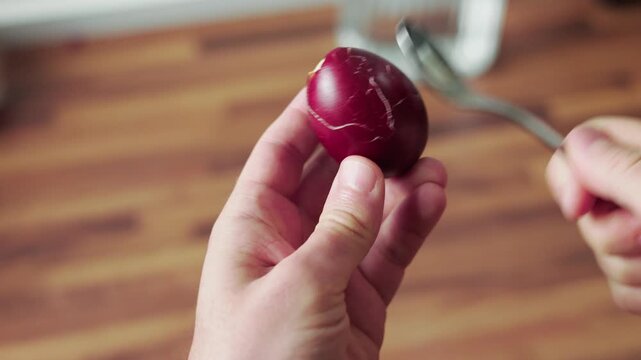 Peeling dyed easter egg shell by hand closeup first person view