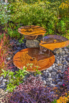 Small patio with modern fountain with assorted plants