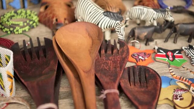 Handmade wooden spoons and traditional African artifacts on display for sale at an open-air market in Amboseli, Kenya